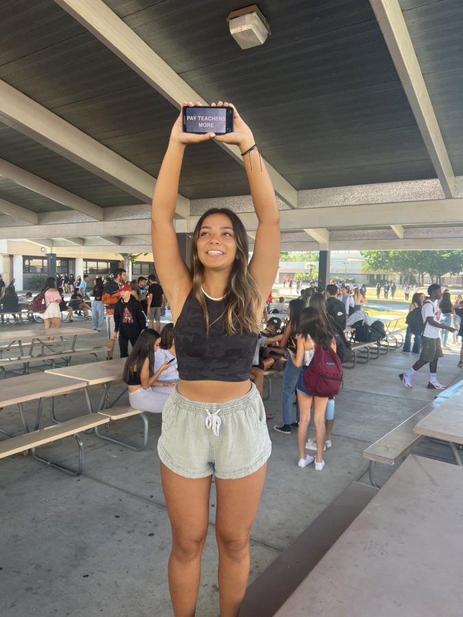 Sofia Salas (12) holds up her phone in support of the current teacher strike during the walkout on Tuesday, Sept. 27th. Her phone reads, Pay Teachers More. 