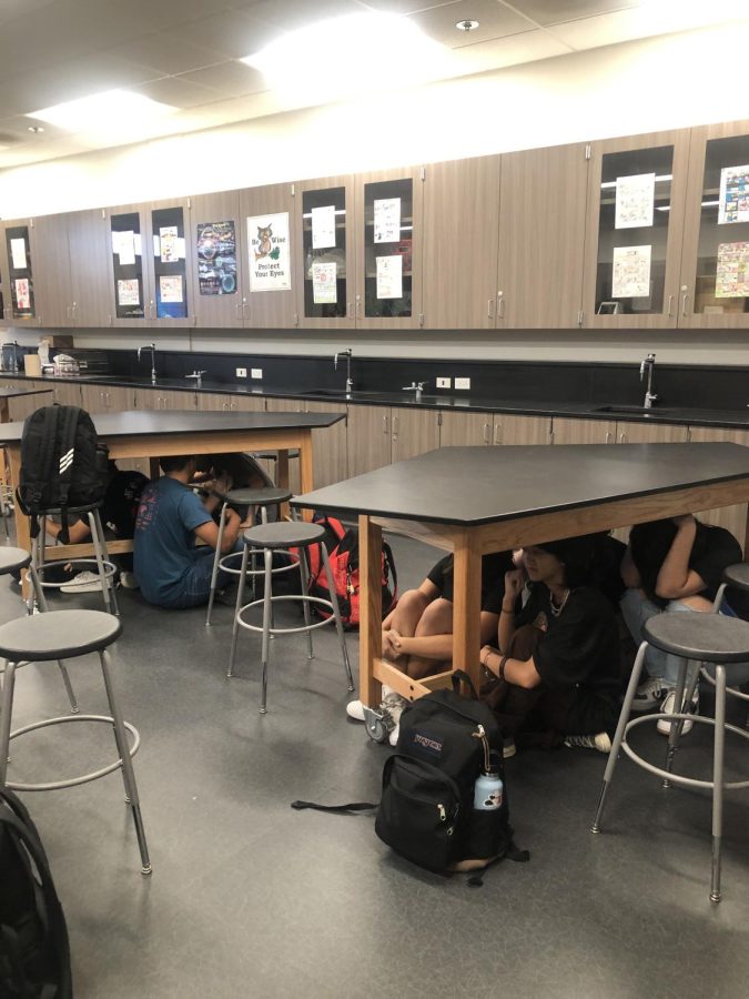 Students protect themselves during the ShakeOut by getting under the tables. Things could fall from the shaking so it is always best to take cover.