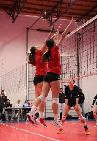 Bella Emanuele closes the block with her teammate at a tournament last season. 