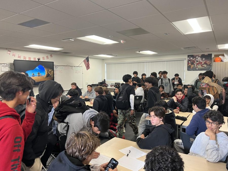 Boys that are interested in starting a mens volleyball program fill the room to attend the meeting. Students write their name on a sign up page to indicate interest before discussing further with the district. 