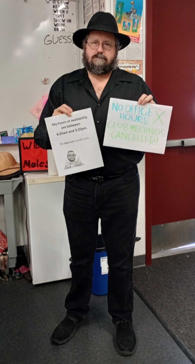 AP Physics and chemistry teacher, Mr. Scott Carter is featured holding a sign saying that his office hours and clubs will be no longer in session. With the teacher collaboration conflicts, students are being affected in numerous ways.