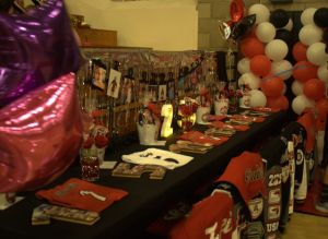 In commemoration of the 2024 seniors, a table was set up decorated with their letterman jackets, jerseys, photos, and gift baskets.