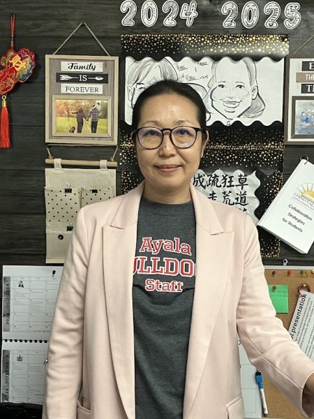 ELD teacher Ms.Fan standing in front of her desk. 