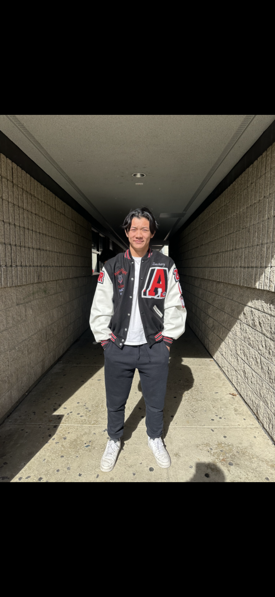 Senior Zachary Zheng in his letterman jacket covered with patches showcasing his accomplishments in football and academics.