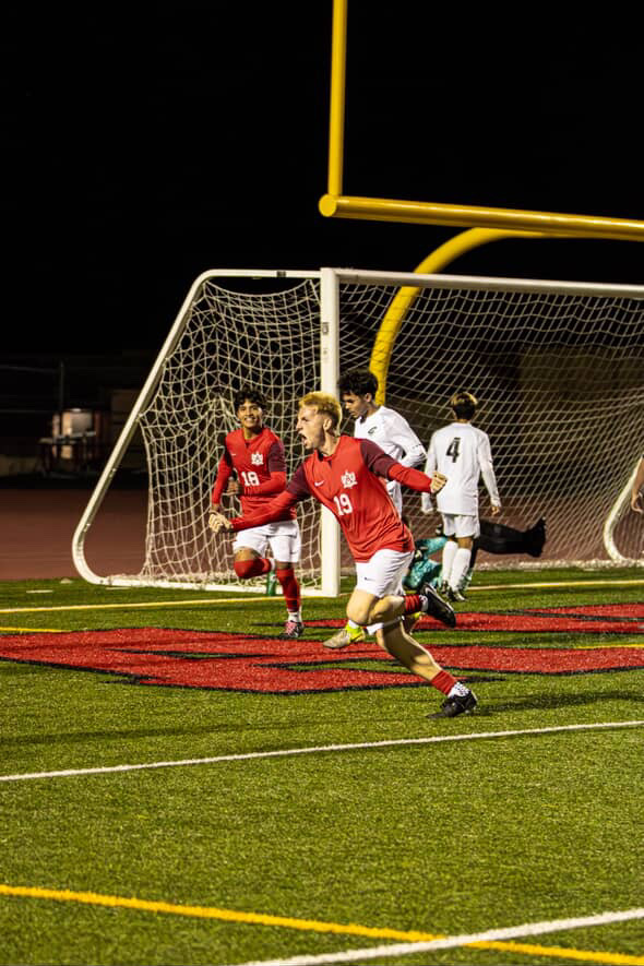 Senior Kyle Henderson (#19) celebrating after a successful penalty kick, one of three goals scored by the Bulldogs during Friday's game.