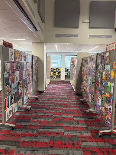 Looking from a students perspective, the artwork displayed creates a colorful mosaic that lights up the library. This helps persuade students passing to stop and take a deeper look at the artwork created by their fellow students. 