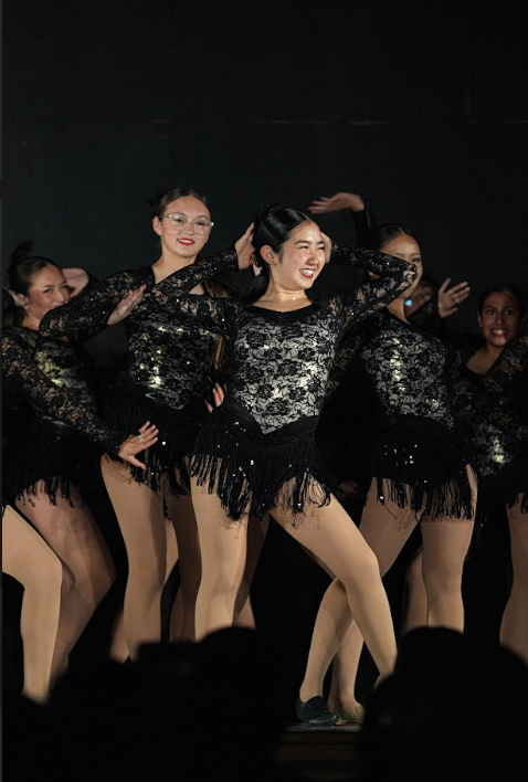 Madelyn Araki (10) flashing a blinding smile to the audience during the Intermediate jazz number, "Applause," which embraces high-energy and showy moves.