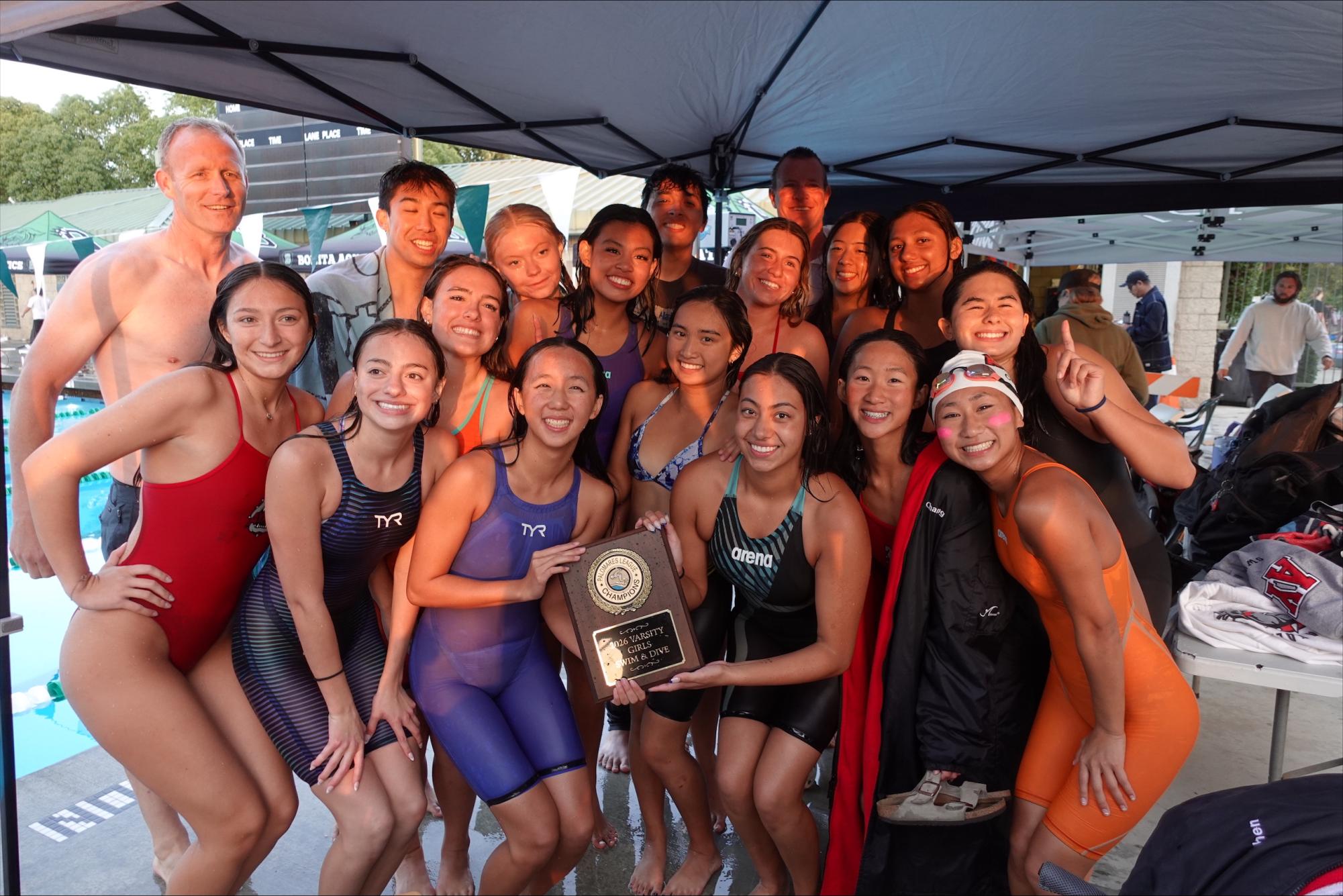 The varsity girls team and swim coaches after jumping into the pool after being awarded league championships.